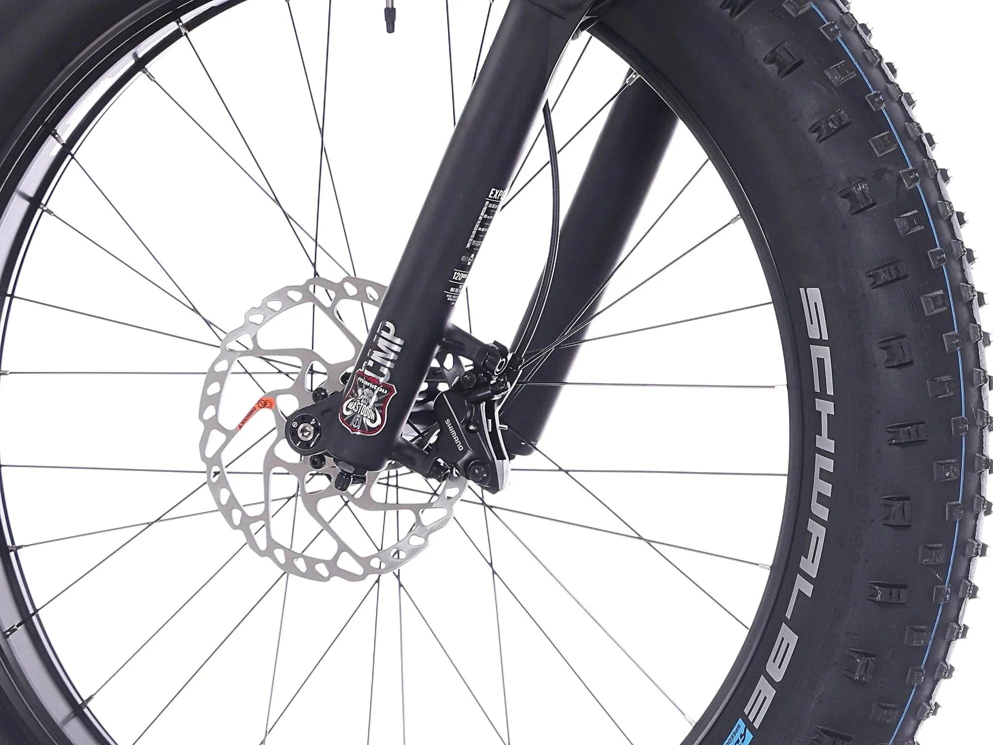 Lähikuva Rock Machine Vyöry E90 -etupyörästä, jossa on paksu Schwalbe-rengas, levyjarru-roottori ja musta jousitushaarukka, joka osoittaa SÄHKÖPYÖRÄT.NETin vankan rakenteen valkoista taustaa vasten.